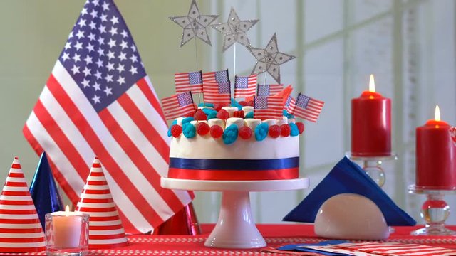 Fourth of July celebration party table with showstopper cake decorated with candy, stars and flag, dolly slider shot.