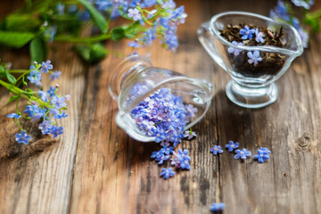 flower tea and a bouquet of forget-me-nots on a wooden background