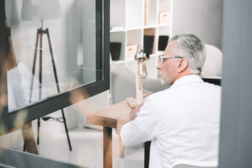 senior businessman near opened window at office