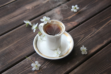 a Cup of coffee and cherry flowers on wooden table
