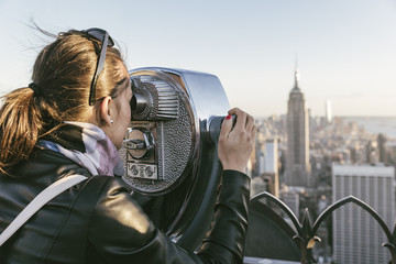 Tourist woman using binoculars in rooftop.