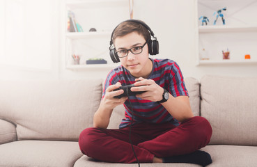 Excited teenage boy playing video game at home