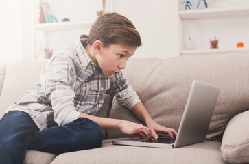 Teenage boy using laptop on couch at home