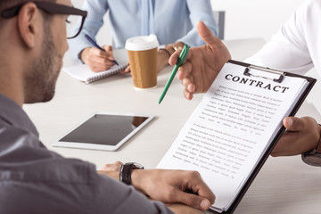cropped shot of executive offering contract to businessman at meeting