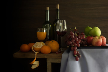 Pile of Fruits and bottle wine with glass put on the plank in dim light / Still Life image and...