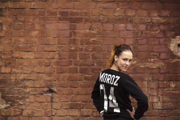 Girl in a sports suit near a brick wall