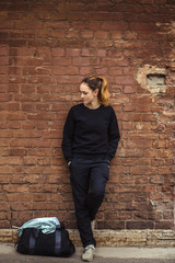 Fototapeta na wymiar Girl in a sports suit near a brick wall