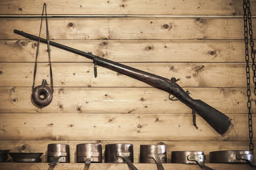 Old hunting rifle with powder flask on wall - obrazy, fototapety, plakaty