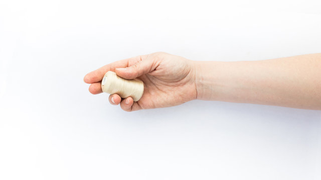 Female hand holding a spool of thread on white background.