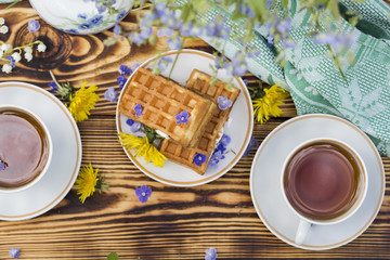 A plate of belgian waffles with and tea cup