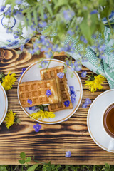A plate of belgian waffles with and tea cup