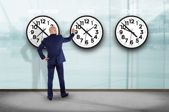 Businessman in front of a wallwith clocks of different country - Jetlag concept