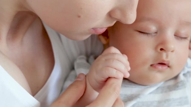 mother kisses her newborn son in a small pen