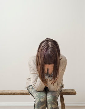 Woman sitting on bench with head in hands