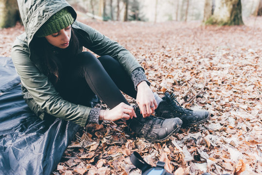 Female hiker putting on hiking boots in forest, Monte San Primo, Italy