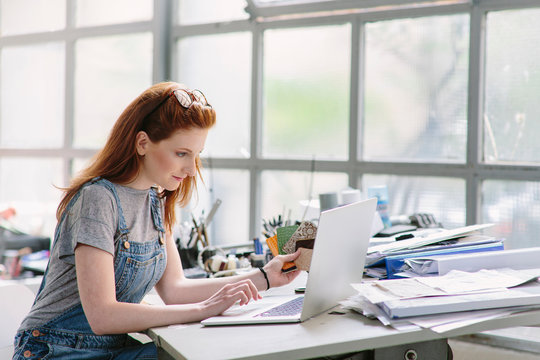 Woman at drawing board using laptop