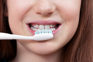Cute smiling girl with permanent and milk teeth brushing her teeth. Dental hygiene.