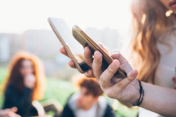 Two young women outdoors, looking at smartphones, mid section, close-up