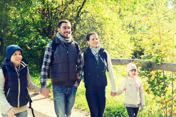 happy family with backpacks hiking in woods