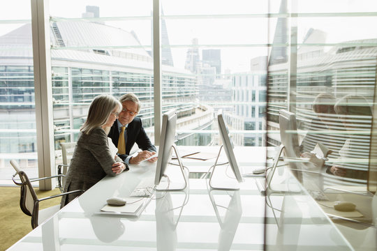 Businessman and businesswoman reading and analysing report, London, UK