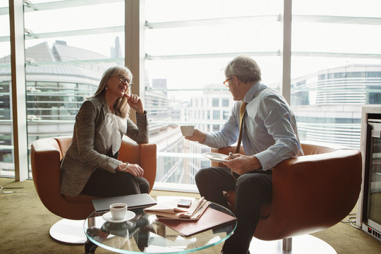 Businessman and businesswoman in coffee area in office, London, UK