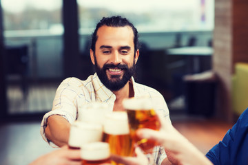 man clinking beer glass with friends at restaurant
