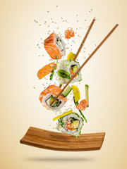 Flying sushi pieces served on plate, separated on colored background
