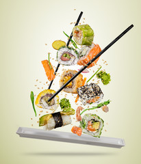 Flying sushi pieces served on plate, separated on colored background