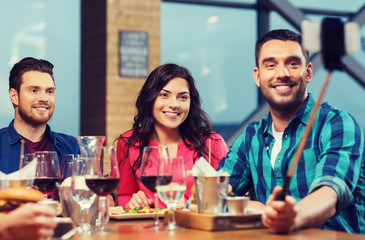 friends taking selfie by smartphone at restaurant