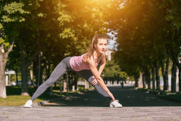 Fototapeta na wymiar Fit fitness woman doing stretching exercises outdoors at park