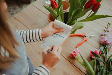 Florist in flower shop making note on order pad, elevated view