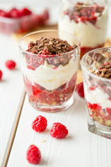 Dessert in Glass with Chocolate, Cream, Raspberry Jam and Pistachio on a Wooden Background
