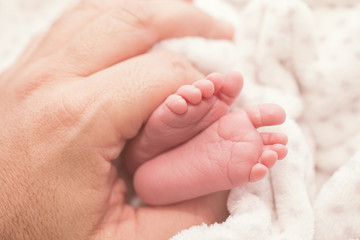 Feet of a newborn baby in the palm of his father