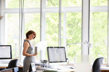 Female interior designer looking at swatch and blueprint in office