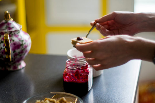 Woman spooning jam onto bread, close-up