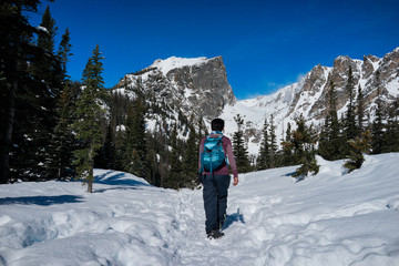 A female hiker hikes in the forest and mountains  with snow in winter.