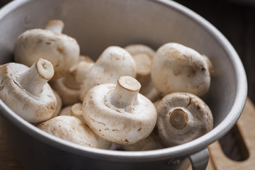 Fresh dirty сhampignon mushroom before peel on the wooden table