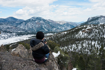 A female hiker hikes in the forest with snow in winter.
