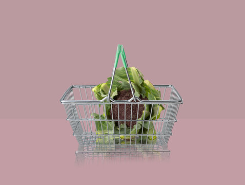 Sicilian purple broccoli in miniature shopping basket on purple background