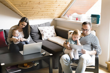 Young parents with little children and gadgets at home.