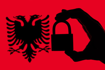 Albania security. Silhouette of hand holding a padlock over national flag