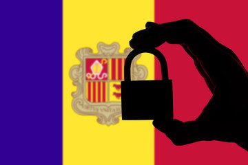 Andorra security. Silhouette of hand holding a padlock over national flag