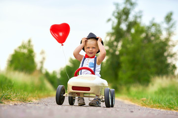 unterwegs mit Tretauto und roten Herzballon