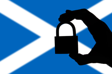 Scotland security. Silhouette of hand holding a padlock over national flag