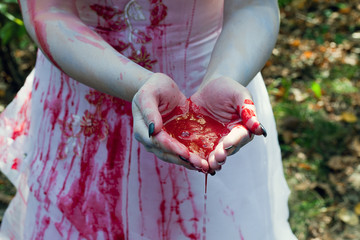 Hands of a girl in white dressed together full of red blood