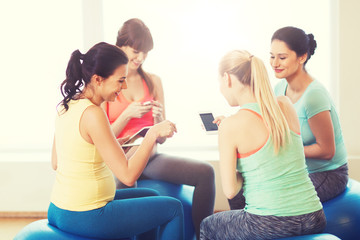 happy pregnant women with gadgets in gym