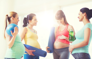 group of happy pregnant women talking in gym