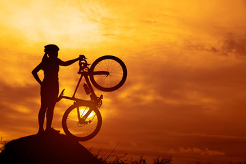 Obraz premium Silhouettes of biker-girl at the sunset