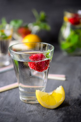 Flavored water with fresh strawberries and mint in glass on a black wooden table with bright details.Selective focus, close up