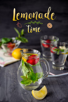 Card with bright phrase Lemonade time and Flavored water with fresh strawberries and mint in glass jars on a black wooden table with details.Selective focus, close up.
